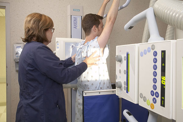 Radiology tech positioning a patient for a n abdominal x-ray.